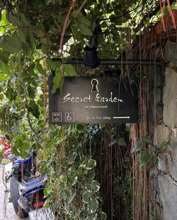 Entrance sign of Secret Garden Hoi An restaurant in a green alley